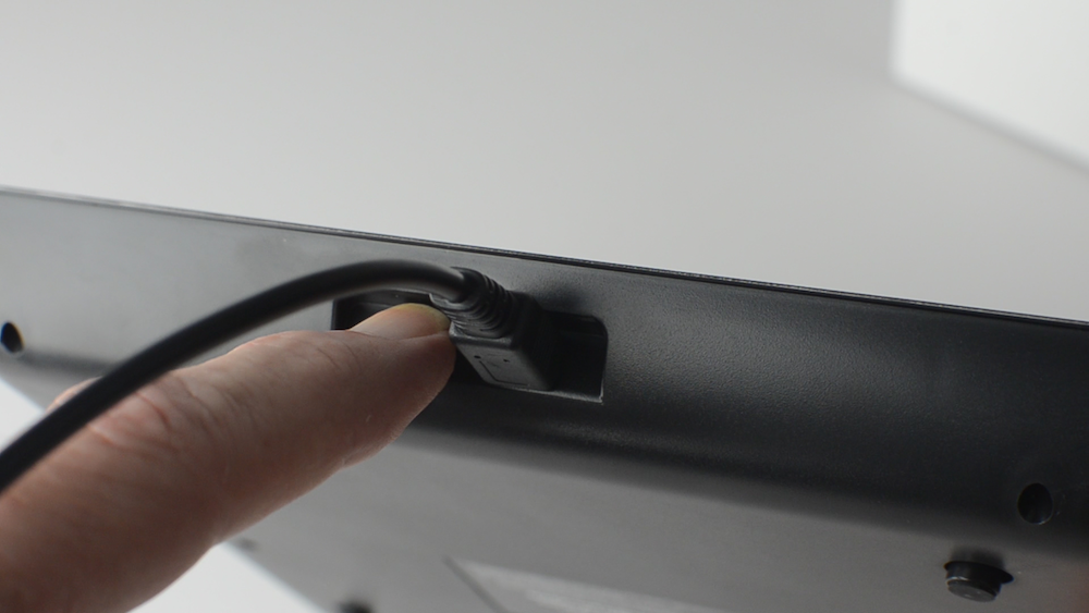 Shows a finger turning on the power switch behind a USB scale
